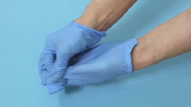 Frau Doktor Zieht Schutzhandschuhe Auf Blauem Hintergrund Aus — Stockvideo