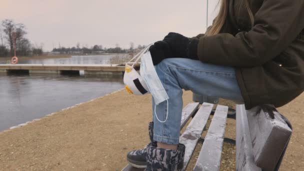 女孩坐在长椅上 拿着防护面罩 — 图库视频影像