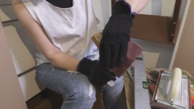 Kadın, eski sandalyeyi zımparalıyor.