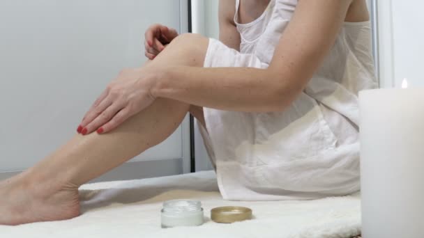 女人在蜡烛旁边放松 并在腿上涂润肤霜 — 图库视频影像