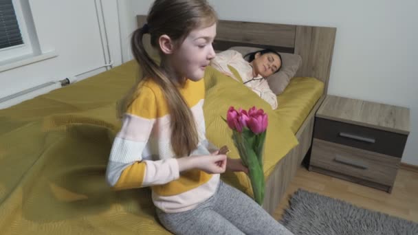 Hija Con Ramo Flores Comiendo Galletas Cerca Madre Dormida Día — Vídeos de Stock