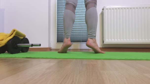Žena trénink její tele svaly na zelené fitness mat 
