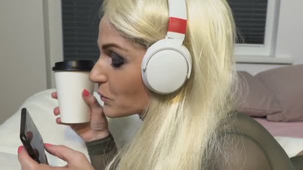 Vrouw Draagt Blond Wig Drinkt Koffie Luistert Muziek — Stockvideo