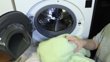 Çamaşır makinesine çamaşır koyan kadın