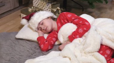 Kız Noel ağacının altında yerde uyuyor.