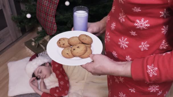 파자마의 소녀는 크리스마스 이브에 근처에서 잠들었다 산타를 우유와 쿠키를 어머니 — 비디오