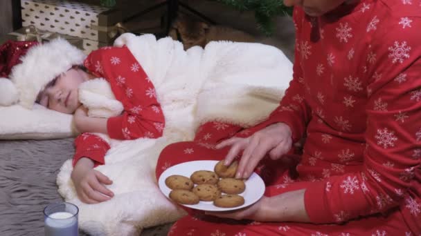 Frau Weihnachts Pyjama Sortiert Kekse Für Den Weihnachtsmann Neben Schlafendem — Stockvideo