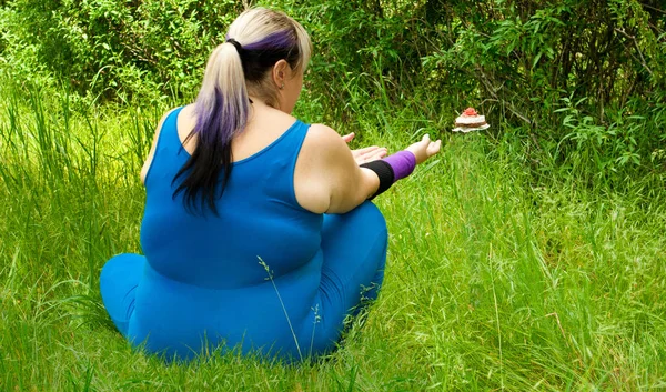 Fat woman wants to lose weight diet view from behind sits on grass image man figure in blue suit bush tree pulls his arms stretches to strive for flying floating cupcake levitation fly off trunk arrangement on the left purple black short nails blue