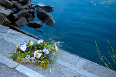 Bir büyük güzel buket çiçegi çelenk, yeşil çim Dinyeper Nehri arka planı gri taş merdiven üzerinde yatıyor ve taş su kenarında akşam Ivan Kupala'nın tatil