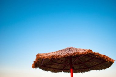 saman ve metal boş temiz mavi gökyüzü yaz sabah hafta sonu tatili bir arka plan üzerinde büyük plaj şemsiyesi yapılmış