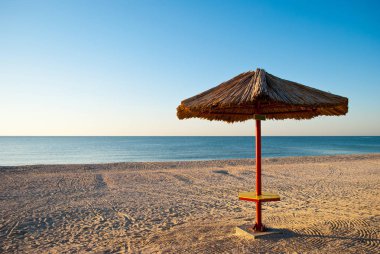 saman ve metal yapılmış büyük plaj şemsiyesi plaj mavi deniz mavi gökyüzü yaz sabah akşam sakin üzerinde duruyor