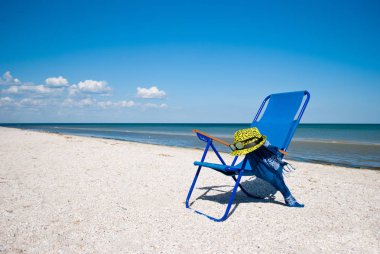Mavi plaj sandalyesi ve şık sarı şapka ile güneş gözlüğü mavi deniz mavi gökyüzü beyaz bulutlar güzel kıyısında yaz tatil plaj kum hafta sonu dinlenme shore manzara