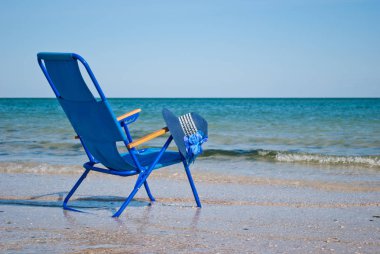 Mavi plaj sandalyesi ve saman mavi deniz mavi gökyüzü deniz kıyısında büyük bir çiçek ile yapılmış şık mavi şapka dalga güzel manzara yaz tatil plaj kum hafta sonu dinlenme shore