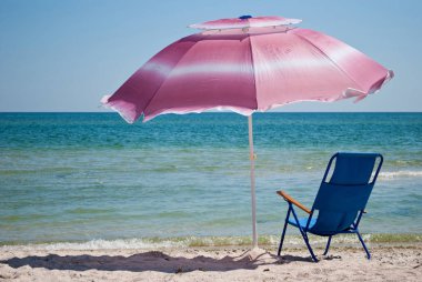 Yaz tatil plaj kum hafta sonu dinlenme manzara mavi plaj sandalyesi ve gölge mavi deniz su mavi gök deniz dalgaları güzel kum adanın kıyısında pembe büyük açık şemsiye