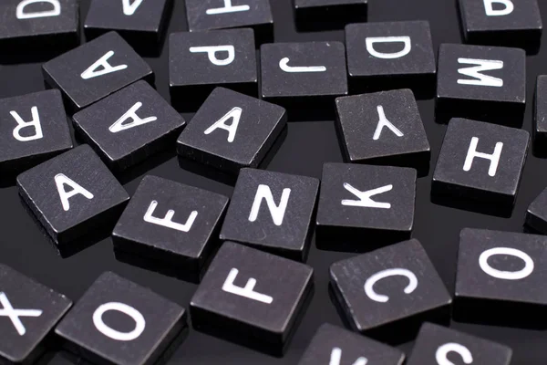 Azulejos de letras negras sobre un fondo negro reflectante — Foto de Stock