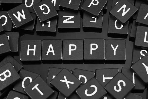 Schwarze Buchstabenkacheln, die das Wort "glücklich" buchstabieren" — Stockfoto