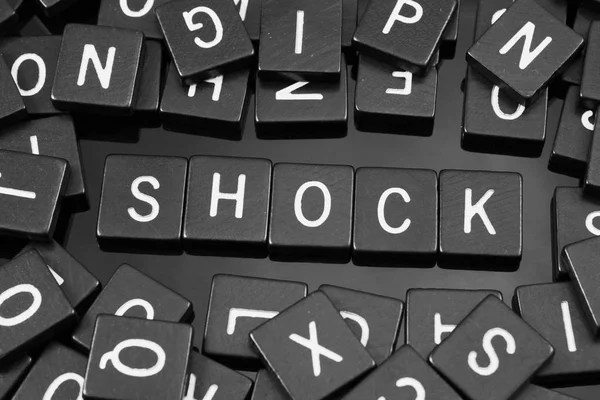 Černé písmeno obkladů, hláskovat slovo "šok" — Stock fotografie