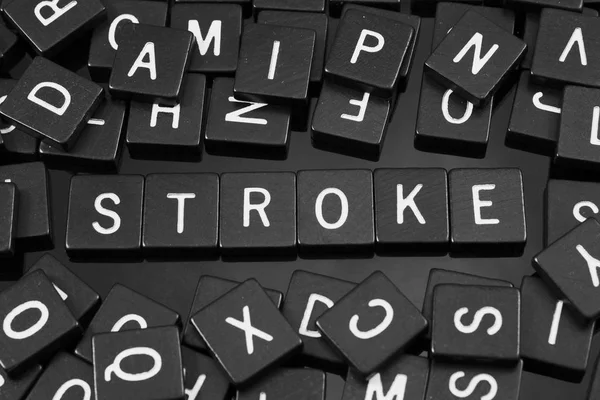 Azulejos de letras negras que deletrean la palabra "stroke " — Foto de Stock