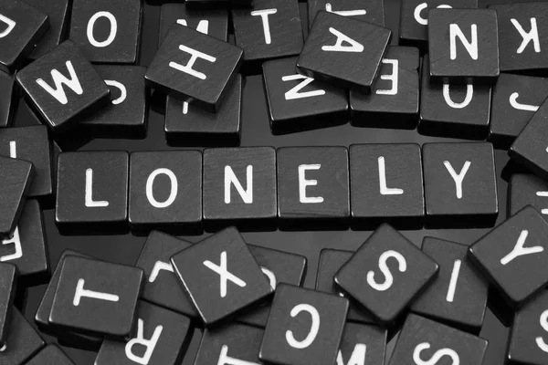 Telhas carta preta soletrando a palavra "solitário " — Fotografia de Stock