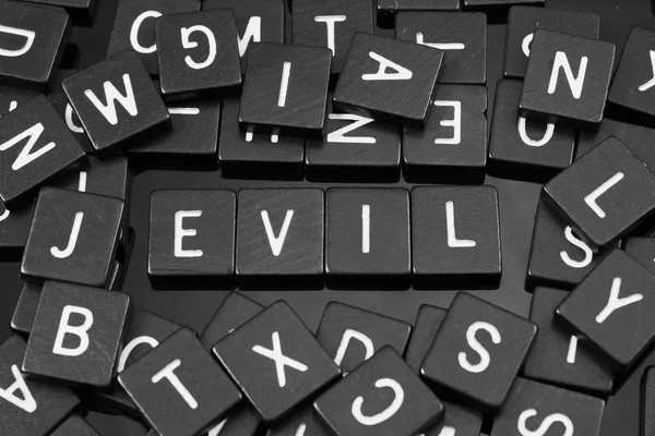 Schwarze Buchstabenkacheln, die das Wort "böse" buchstabieren" — Stockfoto