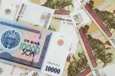 Rusya Federasyonu 'nun arka planında on bin Özbek som banknotunun yakın plan resmi makro banknotlarda yüz ruble.