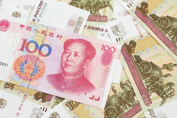 A red one hundred Chinese yuan bank note close up in macro with Russian one hundred ruble bills