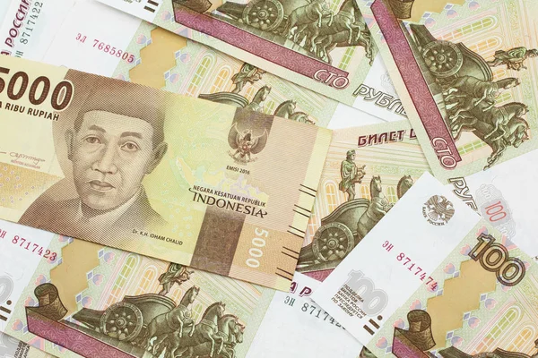 一张橙色的 价值5000印尼盾的钞票 上面印着一百卢布的俄罗斯卢布钞票 — 图库照片