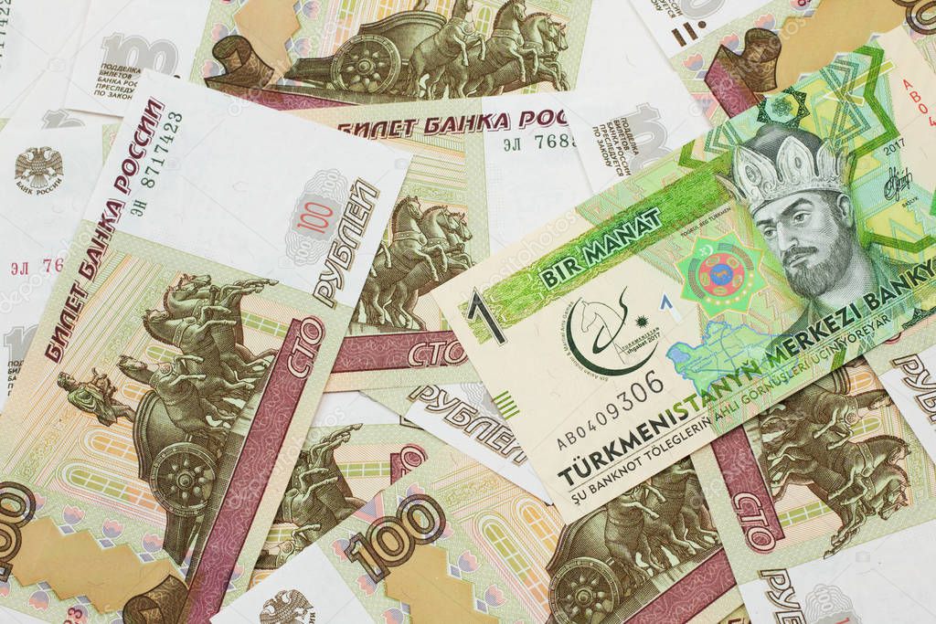 A one manat bank note from Turkmenistan close up in macro with an assortment of Russian one hundred ruble bank notes.