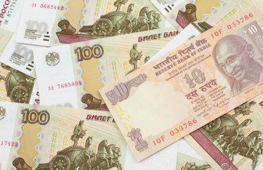 Rus yatağında 100 rublelik banknotlar halinde 10 Rupi 'lik bir Hint banknotunun yakın plan görüntüsü.