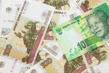 Rusya 'nın 100 rublelik banknotlarından oluşan bir yatakta Güney Afrika' dan gelen 10 rand banknotun yakın plan görüntüsü.