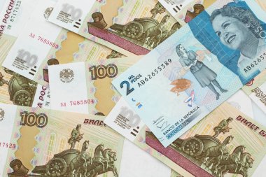 Rusya 'nın arka planında makro banknotlar halinde yüz ruble banknotlar halinde mavi iki bin Kolombiya pesosunun yakın plan görüntüsü.