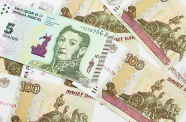 Arjantin 'den gelen beş pezoluk banknot Rus 100 rublelik banknotun arka planında.