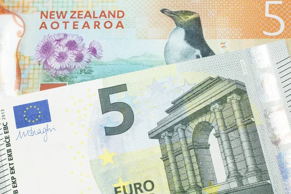 A colorful five dollar bill from New Zealand, close up in macro with a five euro bank note from the European Union