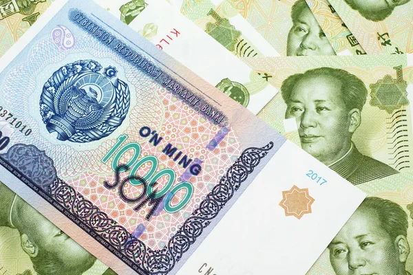 Detailní Záběr Desetitisíce Uzbeckých Bankovek Pozadí Zelených Čínských Jednojuanových Bankovek — Stock fotografie