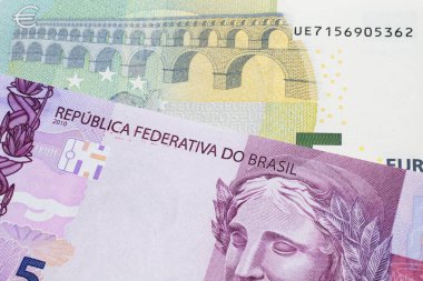 Üzerinde pembe ve mor beş Brezilya reais banknotu olan beş avroluk bir banknot. Makro çekimde..