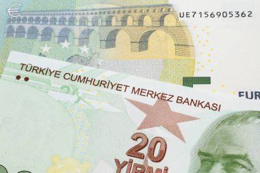 Kırmızı, sarı ve yeşil bir Türk banknotunun yakın plan görüntüsü, makroda beş avroluk Alman banknotuyla birlikte yirmi Türk lirası.