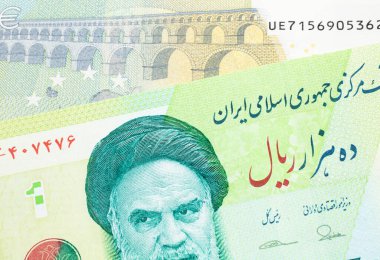 Yeşil İran 'a ait on bin riyal banknotun yakın plan görüntüsü. Üzerinde Fransa' dan gelen mavi ve yeşil beş avroluk makro banknot var.