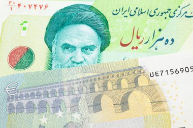 Yeşil İran 'a ait on bin riyal banknotun yakın plan görüntüsü. Üzerinde Fransa' dan gelen mavi ve yeşil beş avroluk makro banknot var.