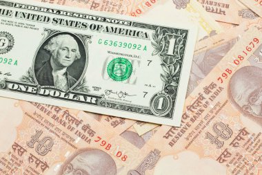 A close up image of a an American one dollar bank note with Indian ten rupee bank notes in macro
