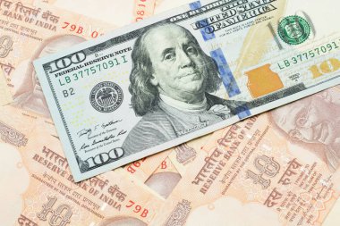 A macro image of a new, blue American one dollar bill close up on a background of Indian ten rupee bank notes from the United States