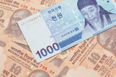 A blue South Korean one thousand won bank note close up in macro on a background of Indian ten rupee bank notes