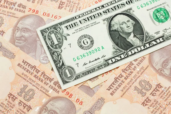 A close up image of a an American one dollar bank note with Indian ten rupee bank notes in macro