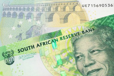 Güney Afrika 'dan gelen yeşil bir onluk banknot Avrupa Birliği' nin Avro Bölgesi 'nden gelen renkli beş avroluk banknotla makroyu kapatıyor.