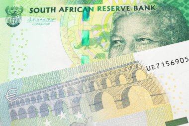 Güney Afrika 'dan gelen yeşil bir onluk banknot Avrupa Birliği' nin Avro Bölgesi 'nden gelen renkli beş avroluk banknotla makroyu kapatıyor.