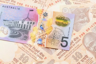 Avustralya 5 dolarlık banknotun yakın plan görüntüsü. Üzerinde 10 rupilik Hint banknotları var.