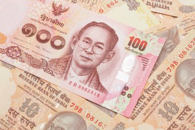 Tayland 'dan gelen kırmızı, 100 baht' lık banknotun yakın plan görüntüsü. Üzerinde 10 rupilik Hint banknotları var.