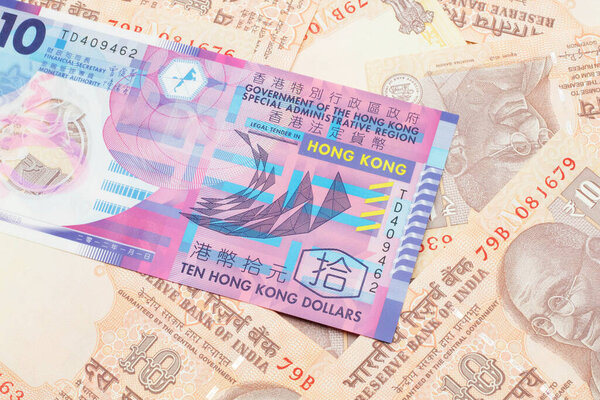 A close up image of a colorful Hong Kong ten dollar bill in macro on a bed of Indian ten rupee bank notes