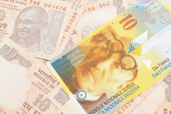 一张来自瑞士的10瑞郎的黄色钞票与10卢比的印度卢比钞票以宏观的形式接近 — 图库照片