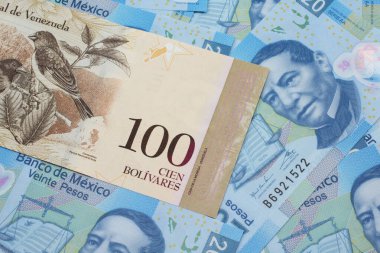 Bir Venezuela 100 Bolivares banknotu, Meksika 'da 20 peso banknottan oluşan bir yatakta makro bankaya yakın.