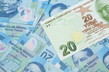 Meksika 'da 20 pesoluk banknotun arka planında 20 lira değerinde yeşil bir Türk banknotunun yakın plan görüntüsü.